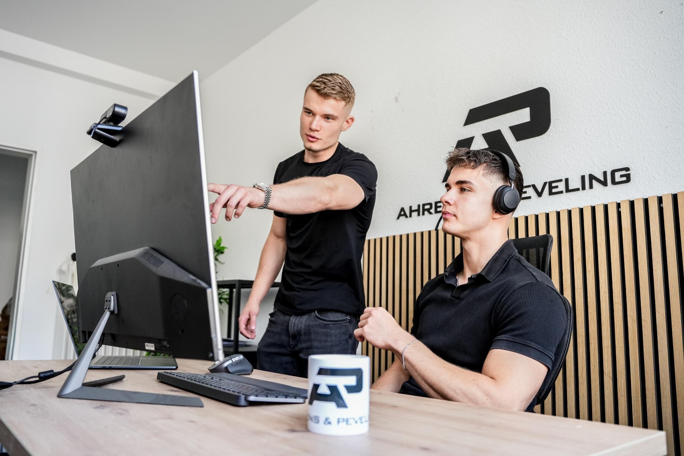 Zwei Kollegen von Ahrens & Peveling besprechen sich gemeinsam an einem Bildschirm im Büro.